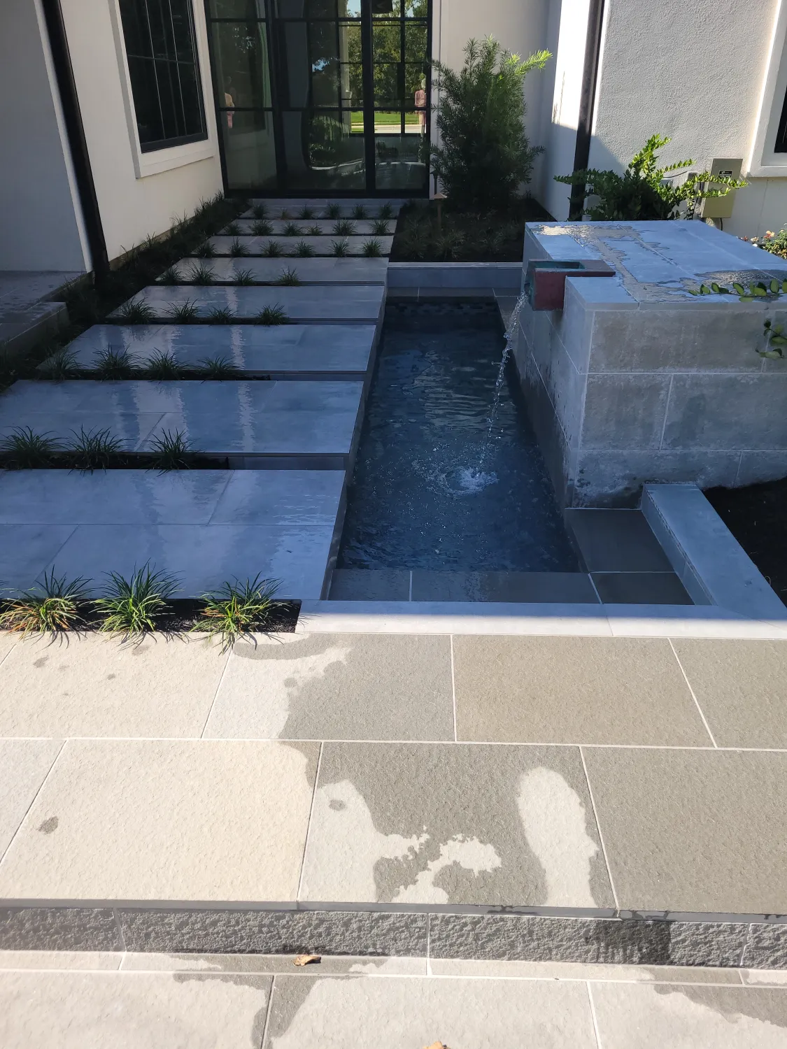 Water fall feature in yard with pathway over it.